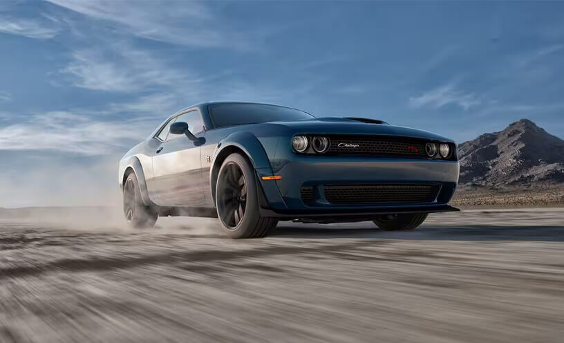 A low-lying angle of a 2023 Dodge Challenger R/T being driven on a track.