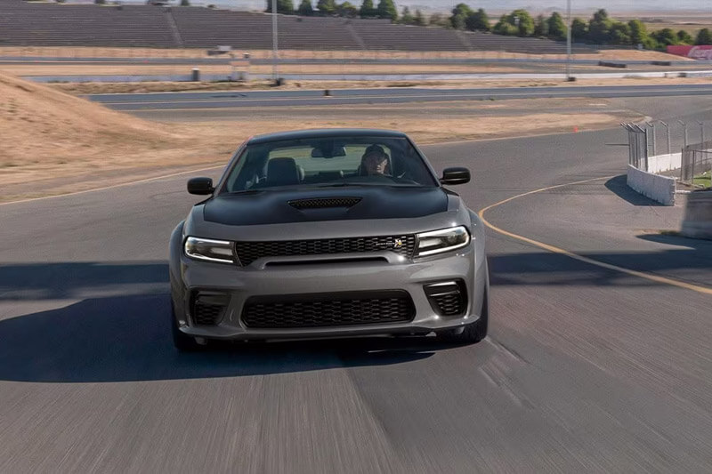 A gray 2023 Dodge Charger Scat Pack taking a curve on a track at a racing complex. 